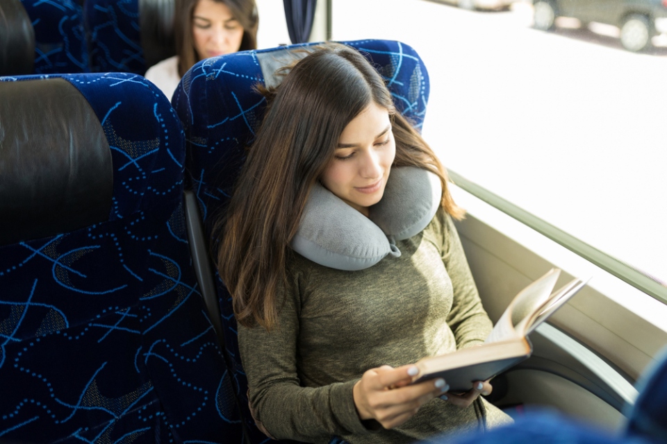 Mujer lee un libro sentada en un bus